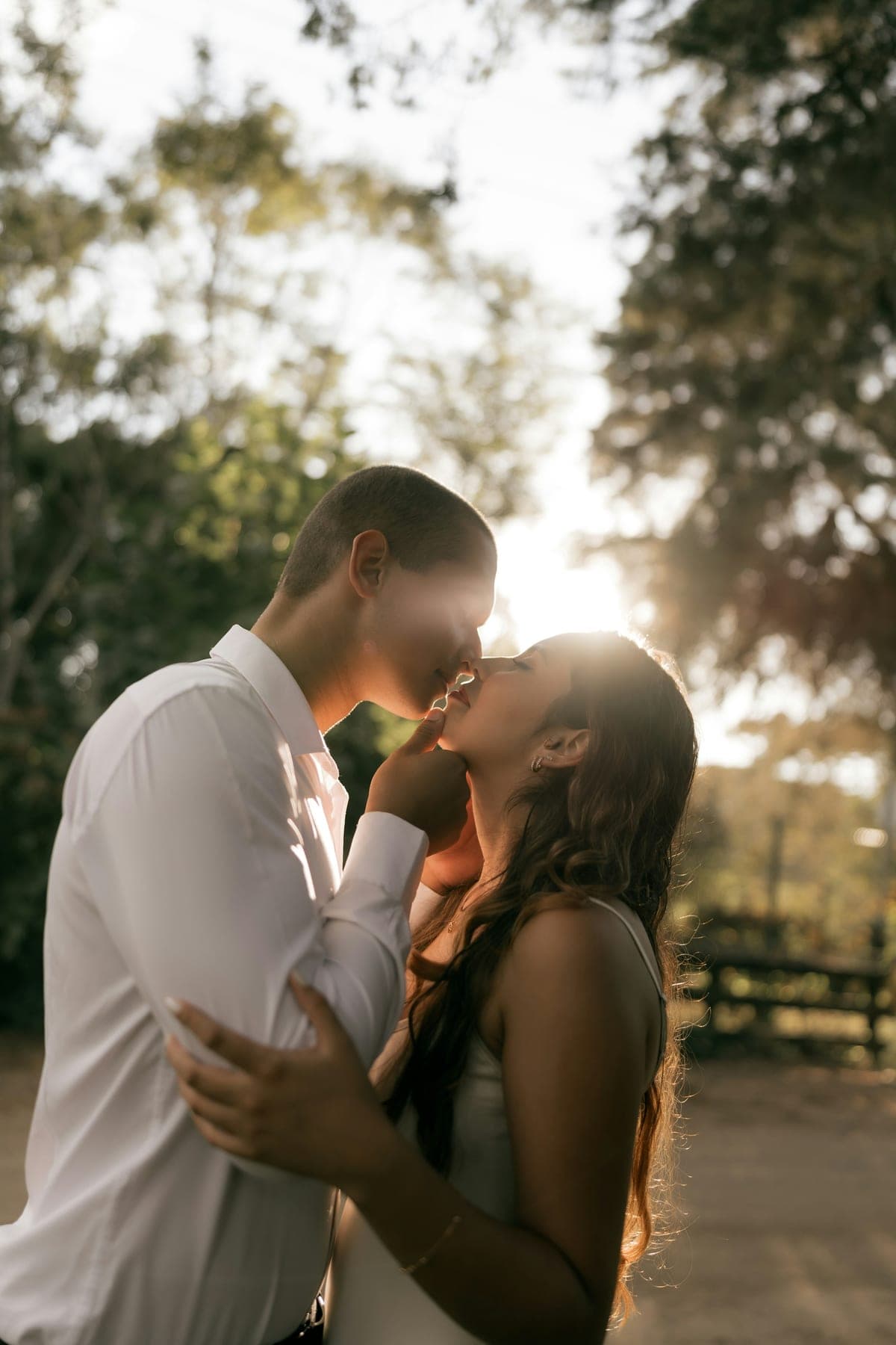 Couple sharing a quiet kiss outdoors in warm light